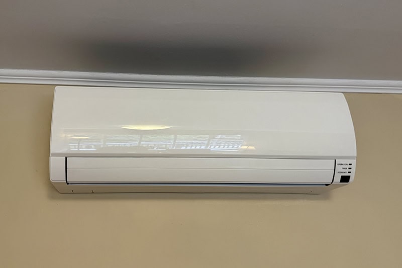 A white, wall-mounted ductless mini-split air conditioning unit.